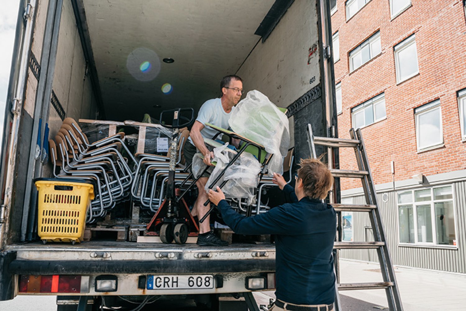 Två volontärer hjälper till att lasta ut möbler från en lastbil.