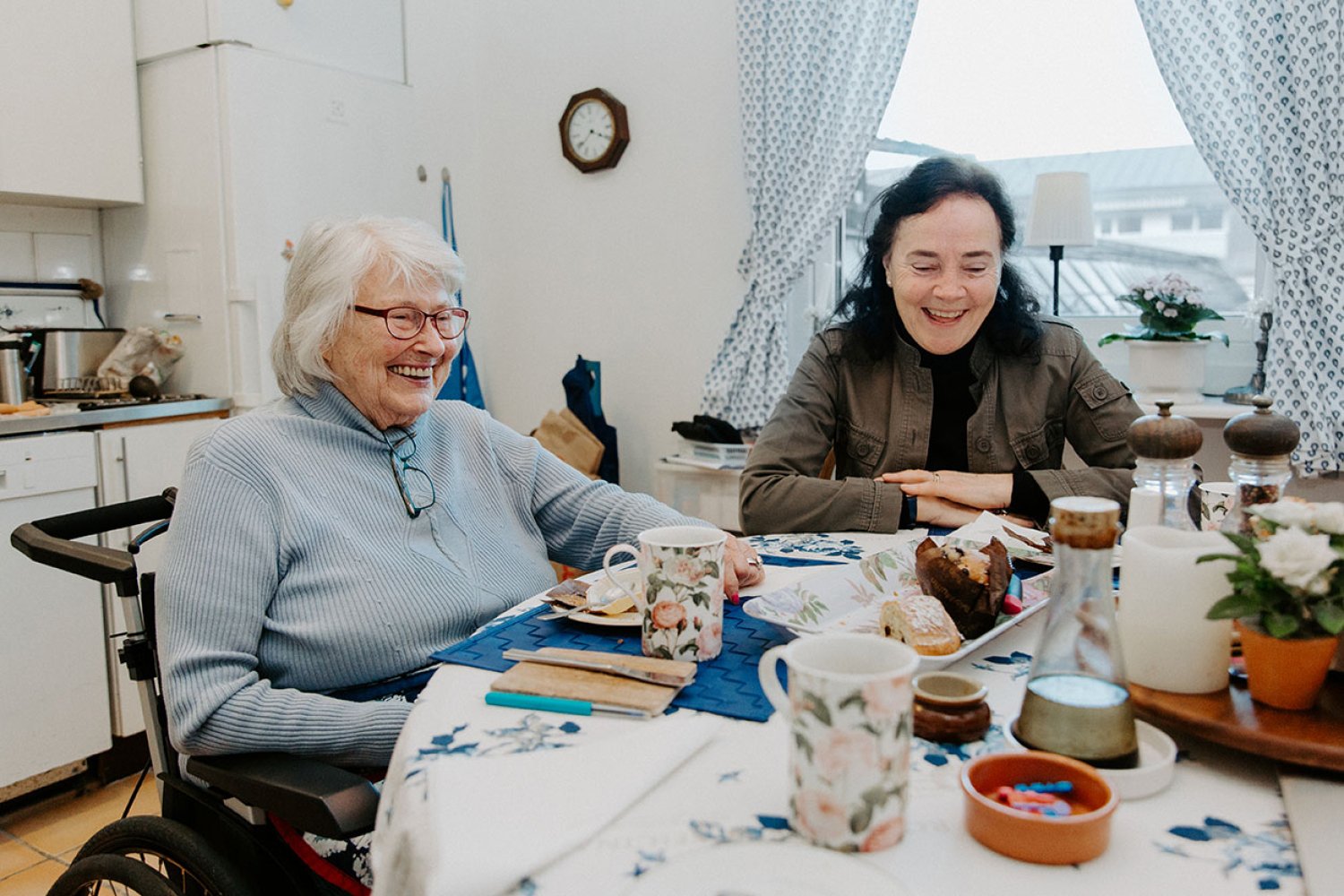 Två personer sitter vid ett köksbord och fikar.