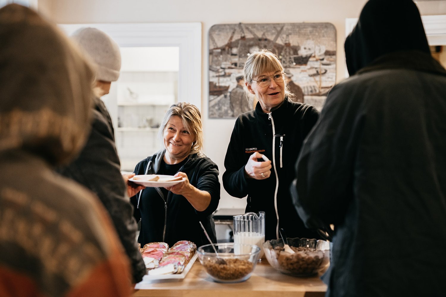 Två glada medarbetare serverar frukost till personer i hemlöshet på Räddningsmissionens frukostcafé.