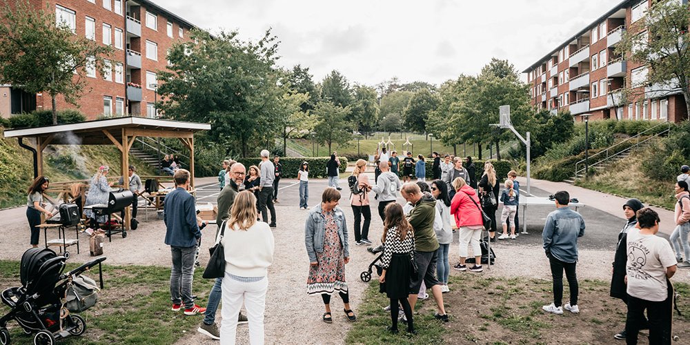 Många människor på Communityskolan Tynnereds skolgård grillar hamburgare och umgås.