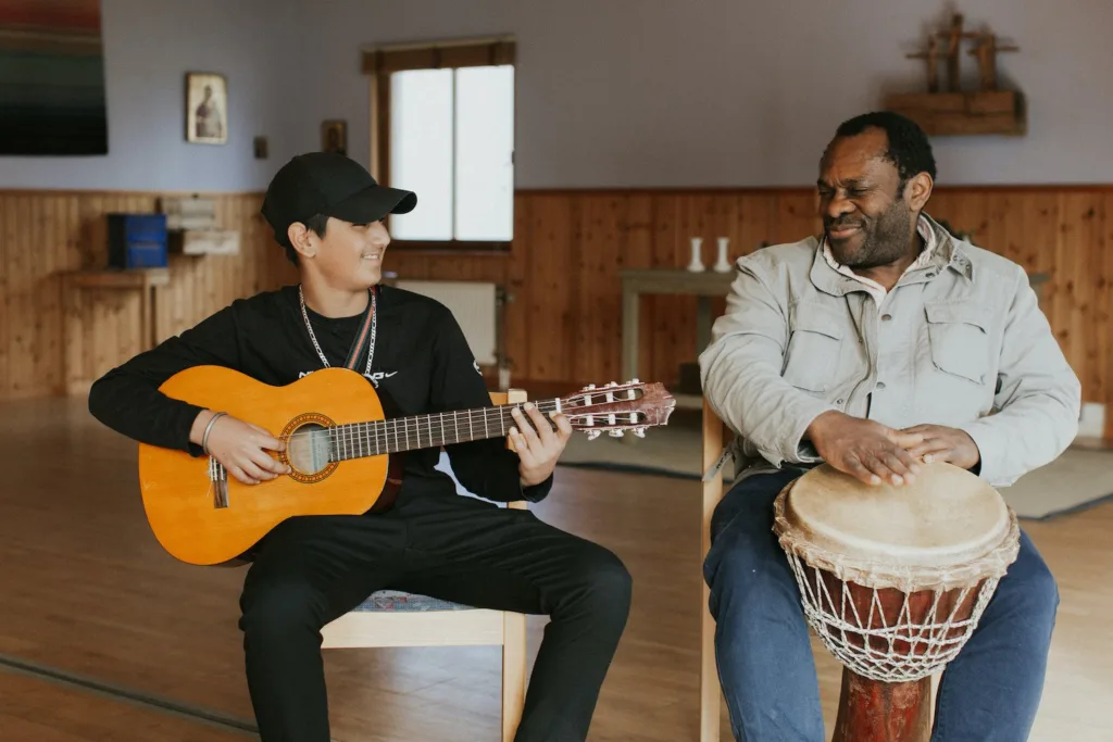 Ungdom spelar gitarr tillsammans med musikpedagog på Svängdörren.