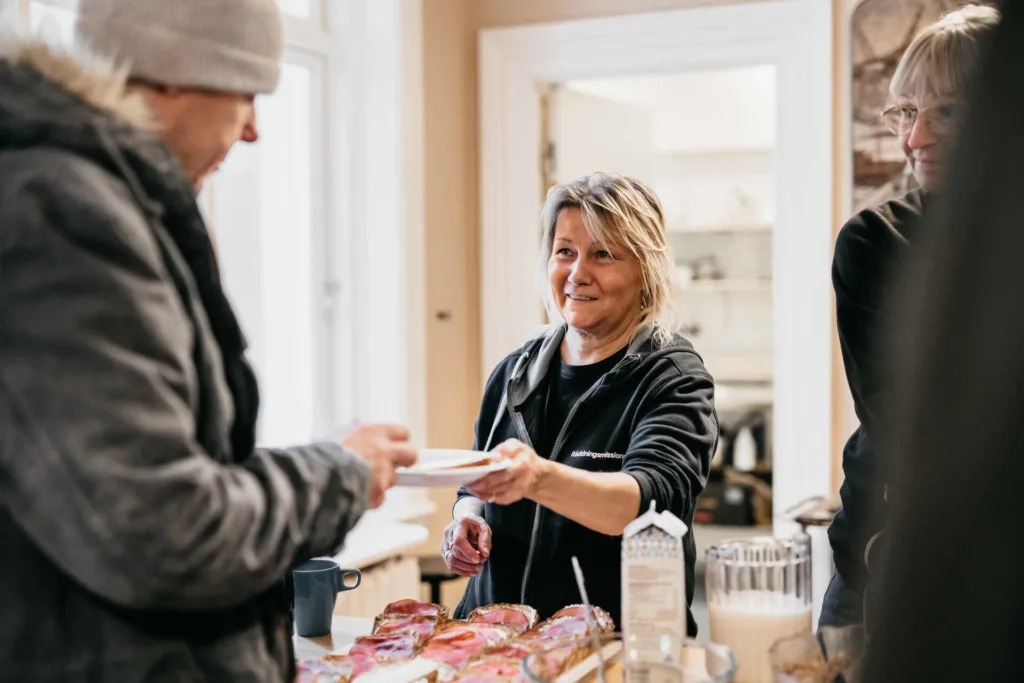 Susanne serverar frukost till en man i hemlöshet