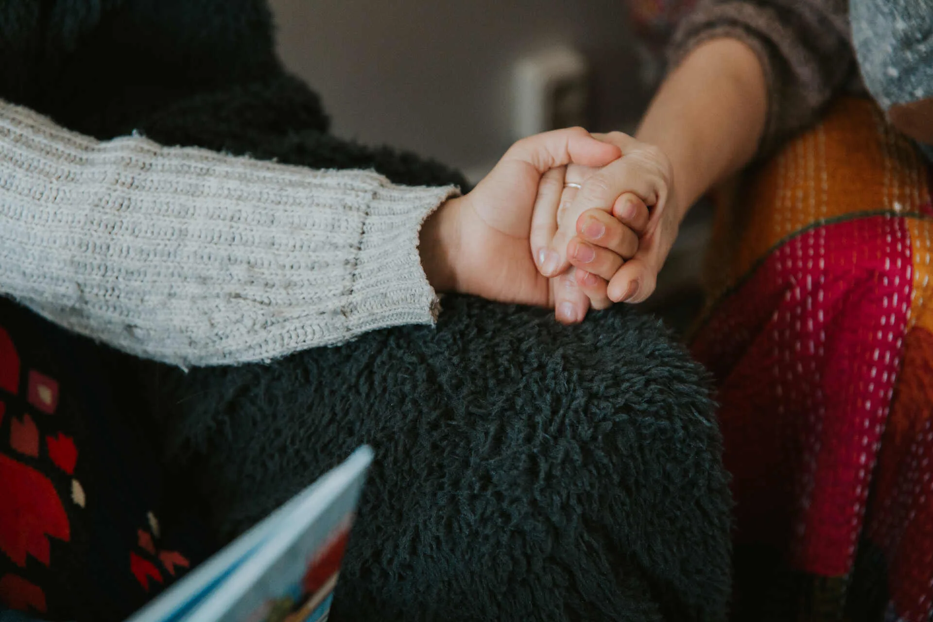 Person sitter i en soffa och håller om handen hos en person i behov av stöd.