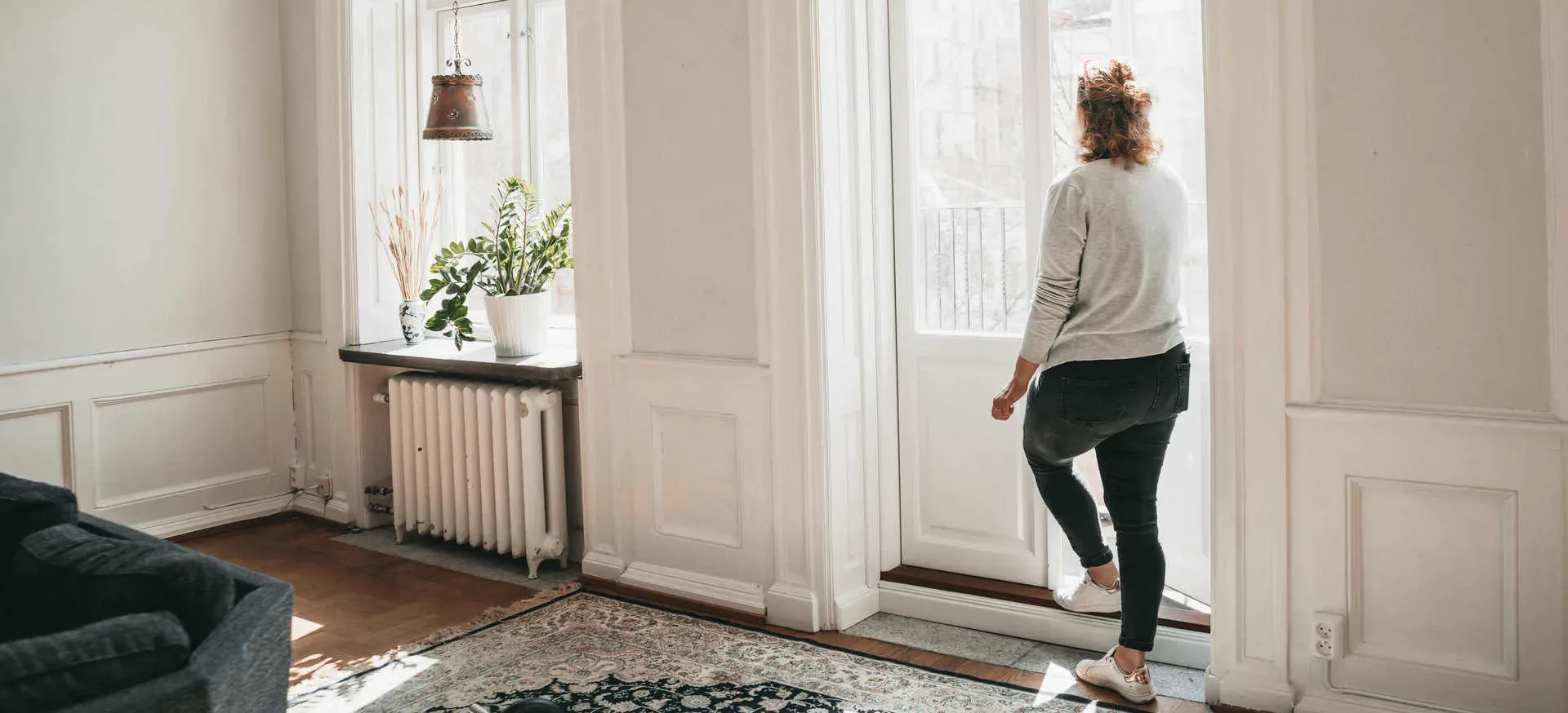 Kvinna tittar ut genom balkongdörren på ett av Räddningsmissionens boenden för personer i hemlöshet.