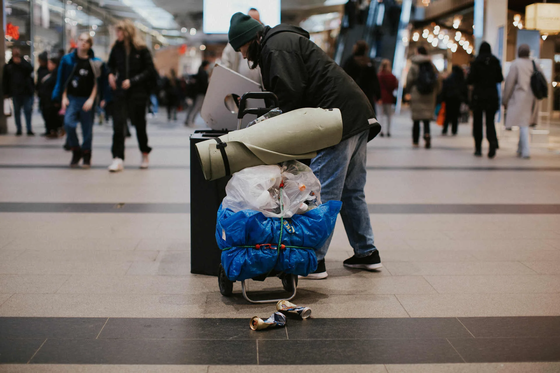 kvinna i hemlöshet letar pantburkar mitt i shoppingen i Nordstan